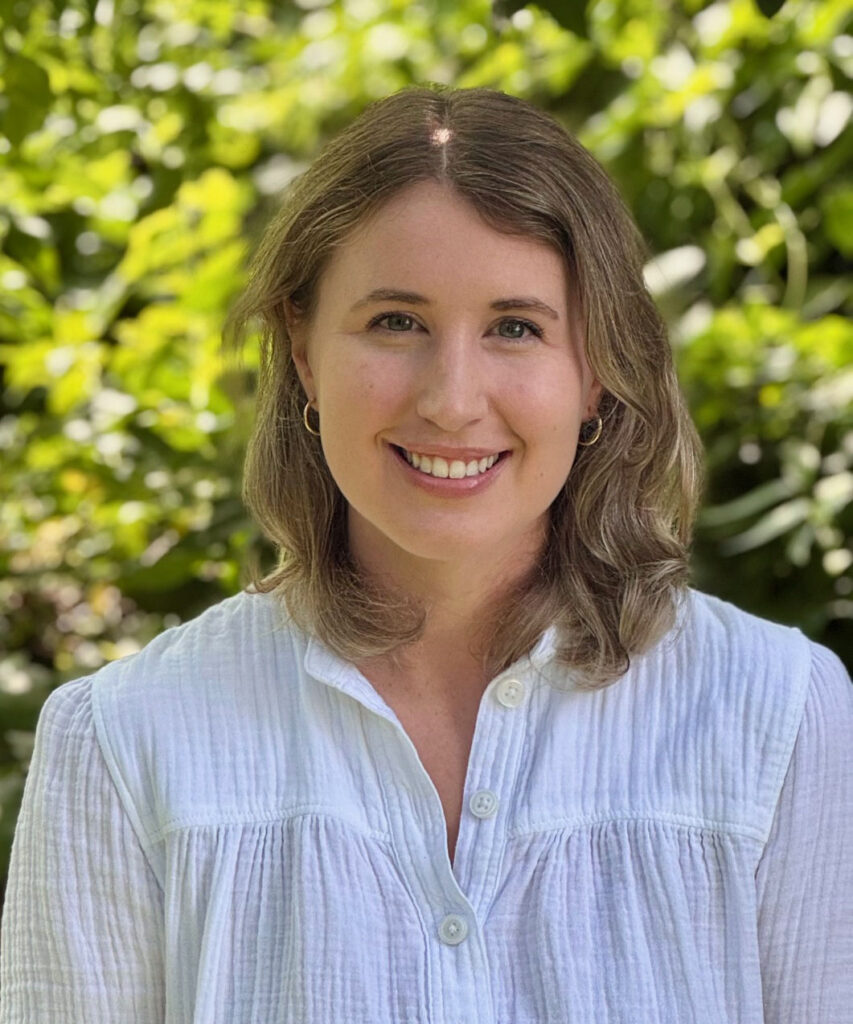 Headshot of Kate Schaller with medium-length blonde hair, wearing a white quarter-button shirt outdoors