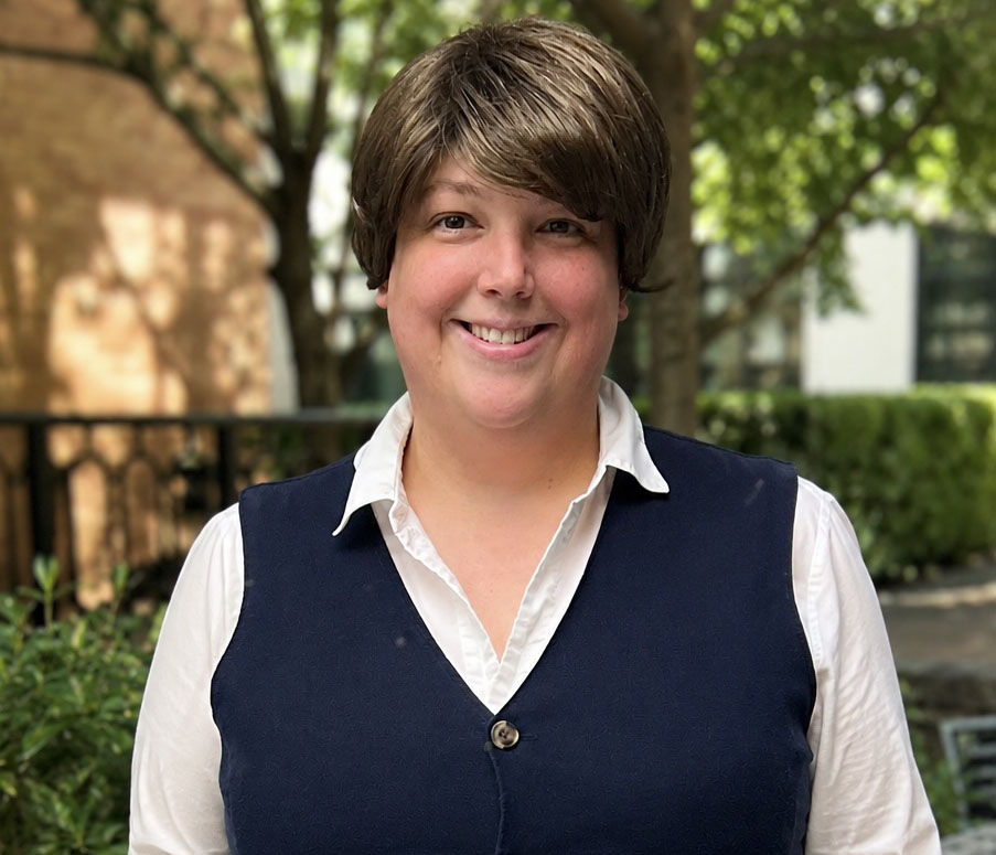 Headshot of Sarah Noah wearing a navy blue vest over a white button-up shirt, outdoors on campus.